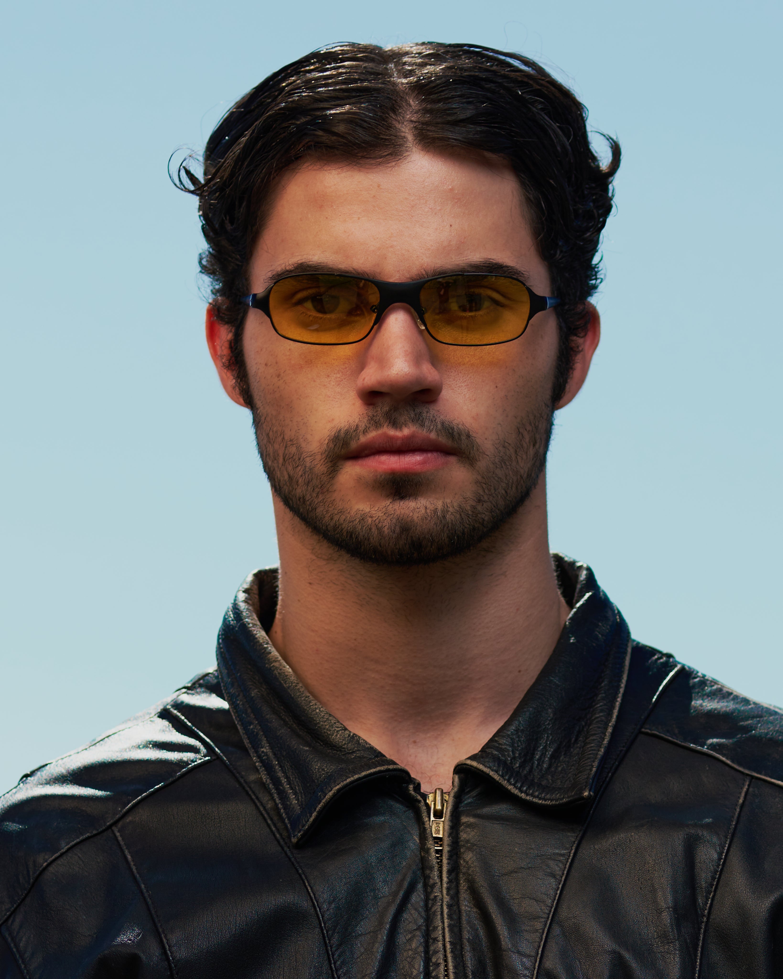 Man with dark hair in 90s / 2000s small frame glasses with yellow lenses and a black frame