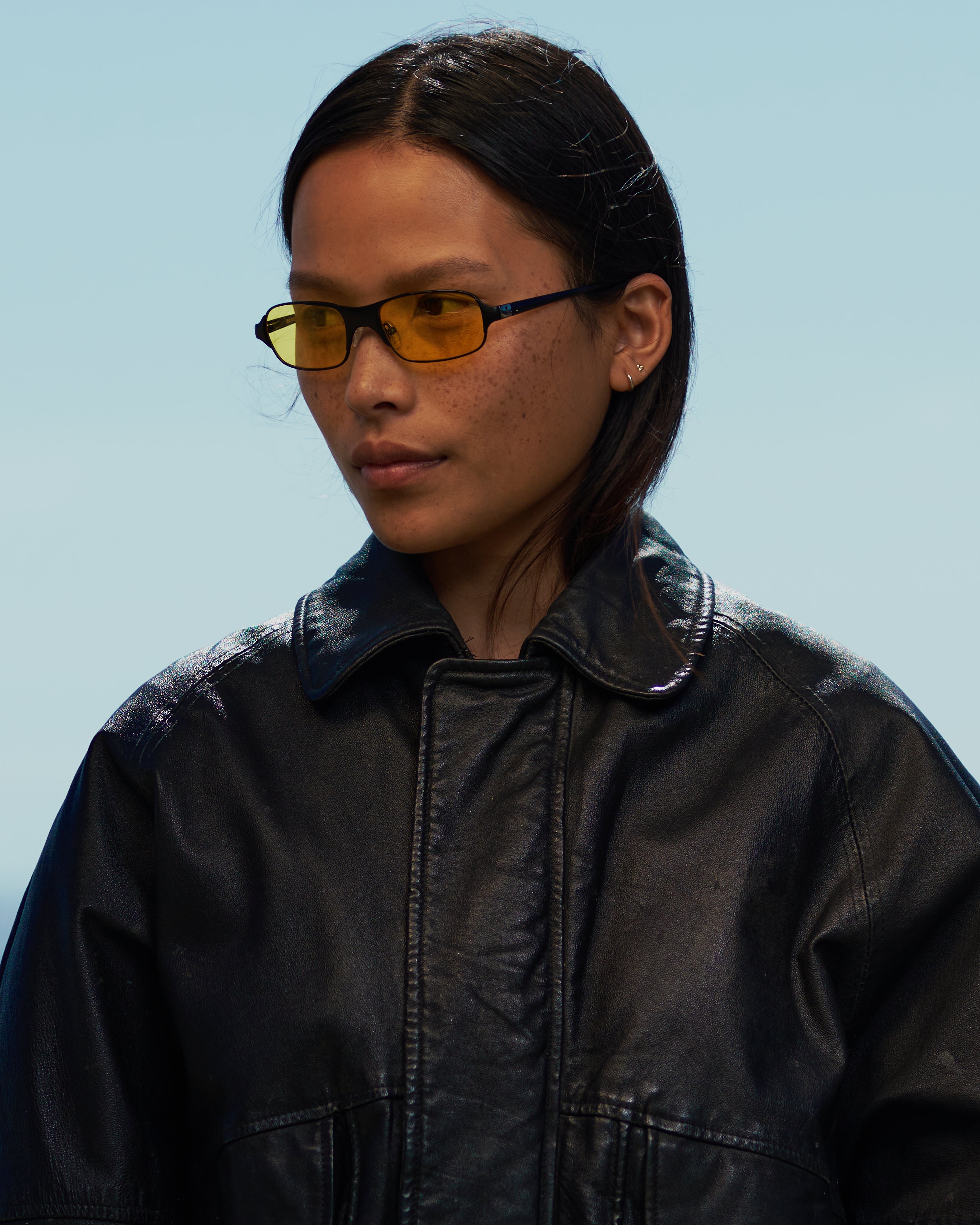 women with dark hair in 90s / 2000s small frame glasses with yellow lenses and a black frame