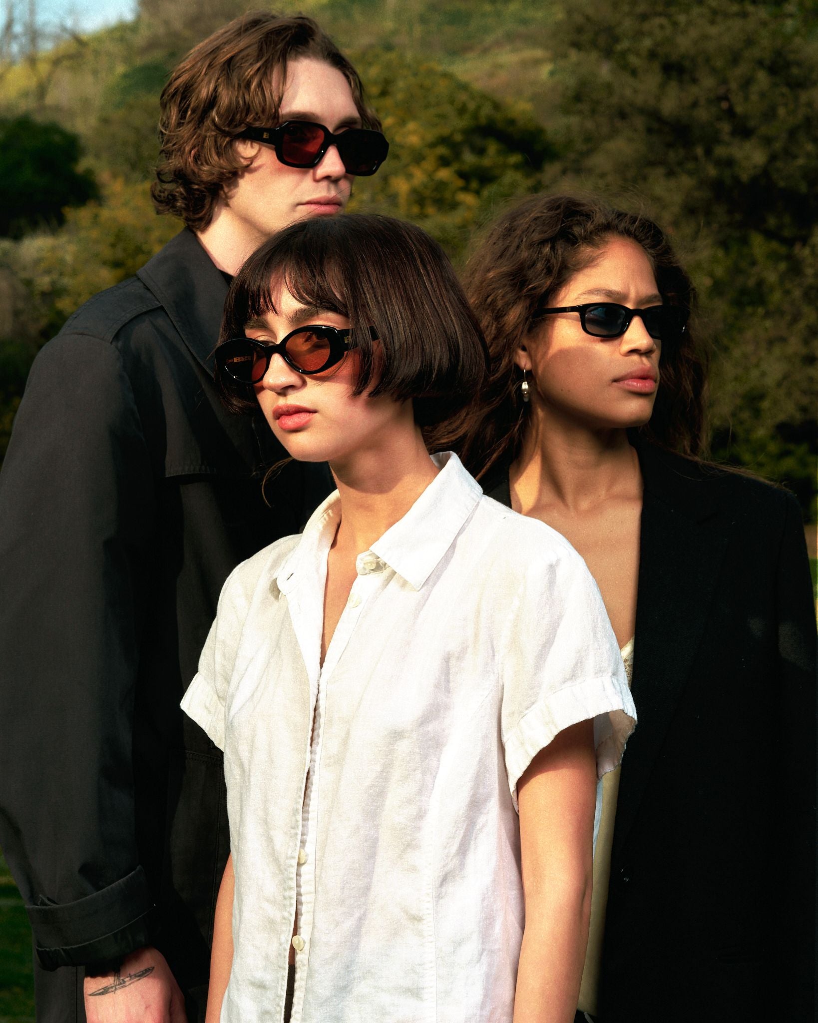Diverse group of models wearing different sunglasses staring off into the distance.